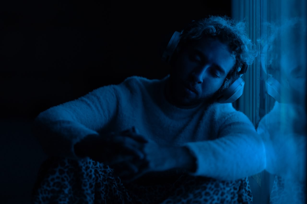 Ibrahim Donia in headphones, leaning against a window